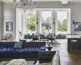 En spisestueide med stort åpent kjøkken, stue og spisestue med store vinduer og blå sofa og stoler
