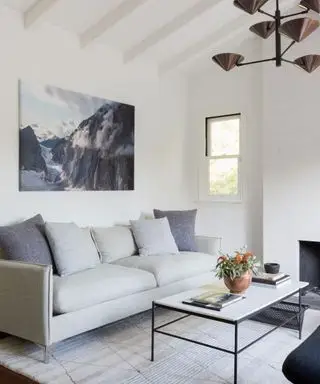 Sala da pranzo bianca con soffitto a volta, divano grigio, tavolino in marmo, opere d'arte sulla parete