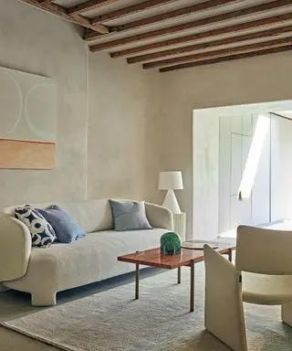 Habitación neutra con paredes texturizadas y sofá curvo color crema.