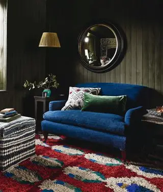 stue med grønmalet shiplap, blå sofa, rød, blå og hvid sofa, puf, bordlamper, pendel, spejl