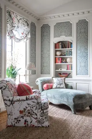 hvid stue med grå damask tapetpaneler, blå chaiselong, blomstret lænestol, matchende rullegardin, kokos tæppe