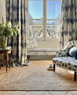 cortina azul y blanca con alfombra de junco y mesa auxiliar