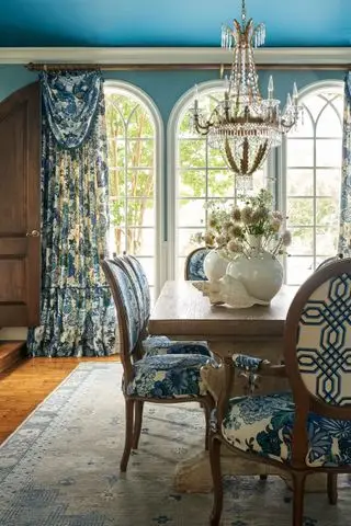 Comedor de estilo francés con araña de cristal y cortinas florales azules