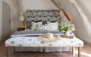 Dormitorio campestre francés con banco y cama tapizados en tela azul y blanca