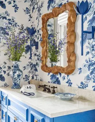 baño con papel tapiz azul y blanco, espejo dorado y tocador azul
