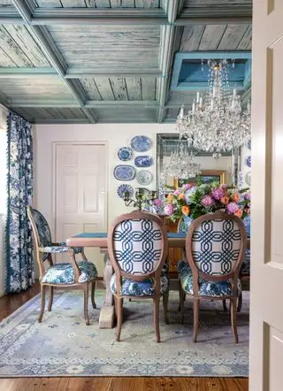 Comedor de estilo rústico francés con techo con paneles de madera y sillas azules y blancas