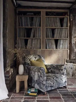 Salon avec bibliothèque et fauteuil chez Morris and Co