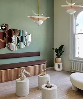 Salon w stylu retro pomalowany na ziemisty zielony kolor i ozdobiony zakrzywionymi meblami