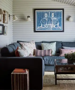 Lille hvid stue med hjørnesofa og vægbeklædning
