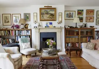 Wohnzimmer mit weißen Wänden und viel Kunst und Antiquitäten, hervorgehoben durch Beleuchtung