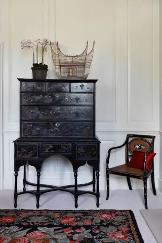 Möbel und Stuhl aus dunklem Holz und gemusterter Teppich