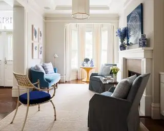 Salón azul y crema con sofá y sillones.