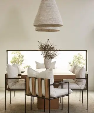 Comedor neutro con dos colgantes bajos, sillas de comedor, mesa de comedor de madera y ventana rectangular baja