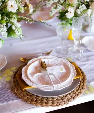 Mesa de color rosa pastel con cubiertos de ratán