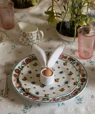 servilleta doblada alrededor de un huevo para parecerse al conejito de pascua en un plato antiguo para la mesa de pascua