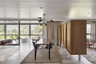 Sala de estar moderna de planta rota dividida por un gabinete de mediados de siglo