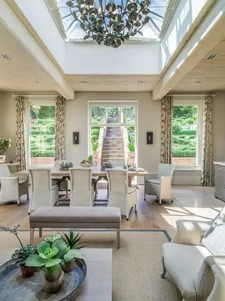 Sala de estar beige de planta abierta con techo acristalado