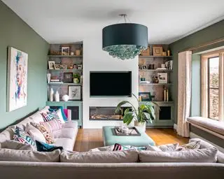 Grønn stue med l-formet sofa og vegghengt tv