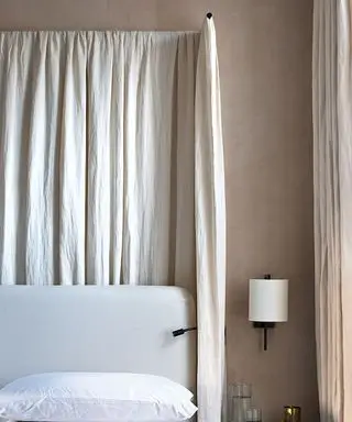 Quarto neutro com dossel creme. Roupa de cama branca, paredes pintadas de bege