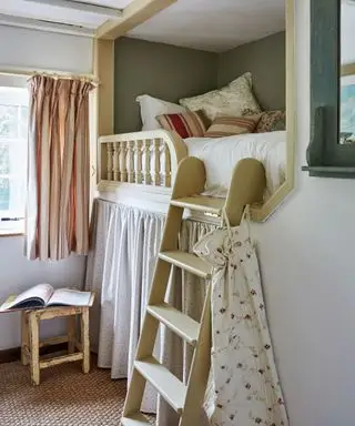 Quarto country, de época, com beliche de madeira, decorado com cobertores e almofadas, cortinas abaixo do beliche, teto com vigas expostas