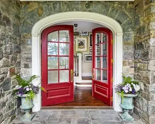 Una puerta de entrada doble arqueada, pintada de rojo con ventanas de vidrio
