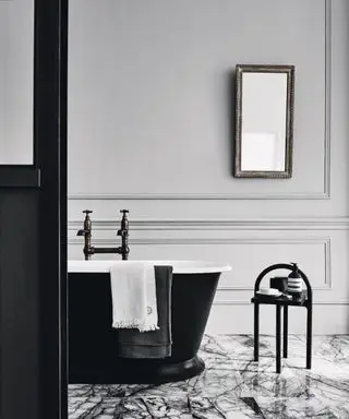 Baño con paneles grises, molduras, suelo de mármol, bañera negra