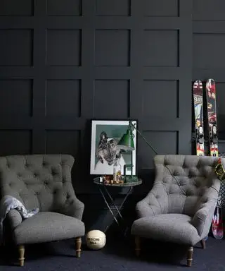 Sala de lectura de biblioteca con paneles de madera de color gris oscuro, par de sillones vintage grises a juego