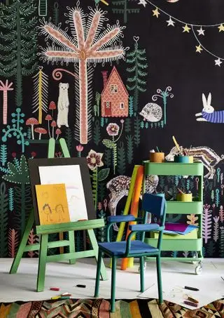 habitación infantil con mural de Lucy Tifney, sillas infantiles, caballete y mueble de almacenamiento