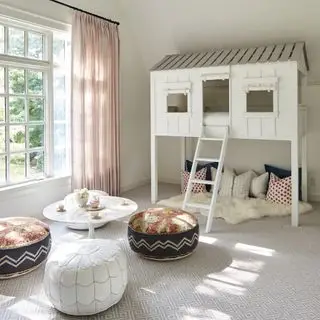 sala de juegos con casa en el árbol, cojines, pufs, mesa baja, alfombra, cortinas rosas