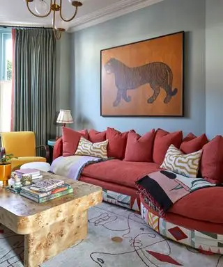 farverig stue med gul accentstol, mørk pink sofa, lyseblå vægge og tigerkunst