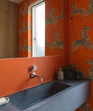 Orange pudderum med zebra print tapet og mørkegrå vask