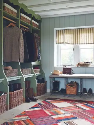 Et eksempel på mudroom-ideer, der viser et lyst mønstret gulvtæppe og grøn opbevaring med flettede kurve