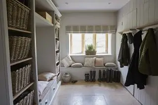 Et eksempel på mudroom-ideer, der viser et mudroom med bænk med hynder under et vindue og opbevaring på væg og knage