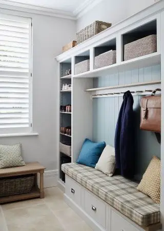Et eksempel på mudroom-ideer, der viser en tartan bænk med puder og knage foroven