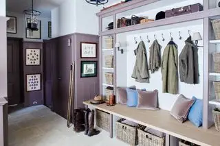Et eksempel på mudroom-ideer, der viser et lilla mudderrum med vægpaneler, flettede kurve og en bænk med puder