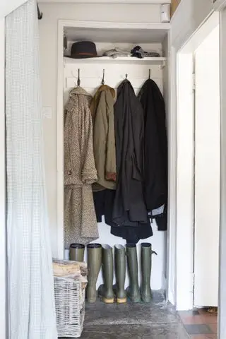 Et lille walk-in closet omdannet til et mudderrum med gummistøvler og frakker