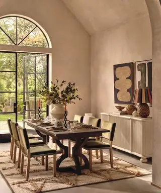 comedor moderno con una gran mesa de comedor de madera oscura y una alfombra neutra con textura
