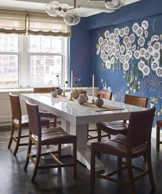 En spisestueveggidé med et dypblått tapet med ikke-repeterende hvitt blomsterdesign og spisestuestoler i brunt skinn