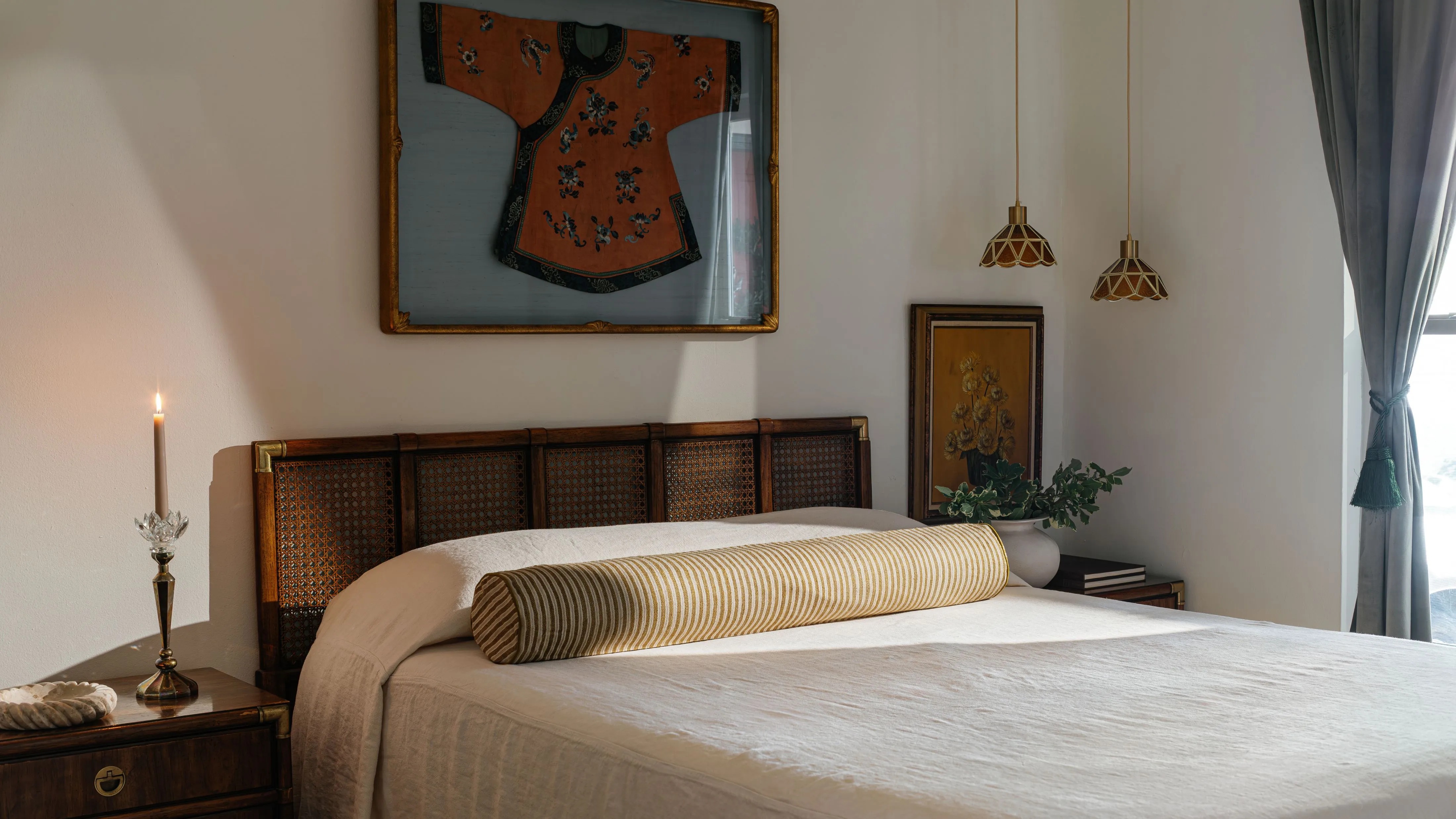 杖のヘッドボードとシングルストライプのボルスター枕を備えたベッドを備えた静かなベッドルーム' loading='lazy' title=