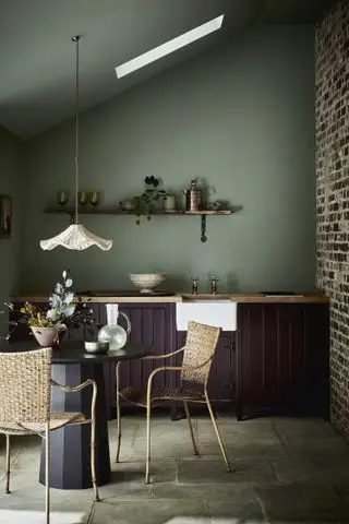 Esszimmerküche aus dunklem Holz mit salbeigrüner Wand und Rattan-Pendelleuchte