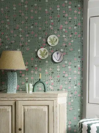 Rosa und grüne Tapete hinter der Konsole mit Tellern an der Wand und Lampe
