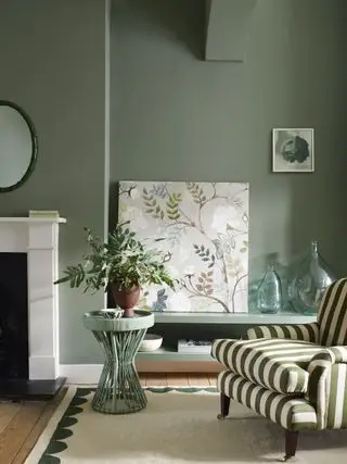 Wohnzimmer mit salbeigrünen Wänden, Marmorkamin und grün gestreiftem Stuhl