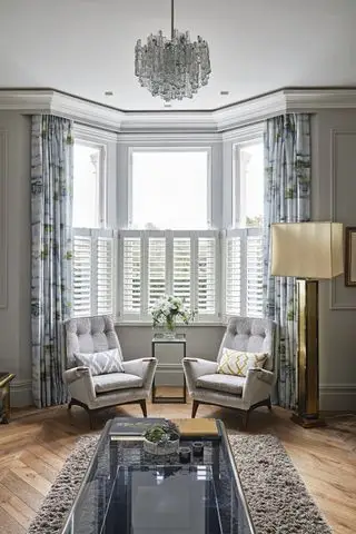 Janela saliente da sala de estar decorada com cortinas e persianas