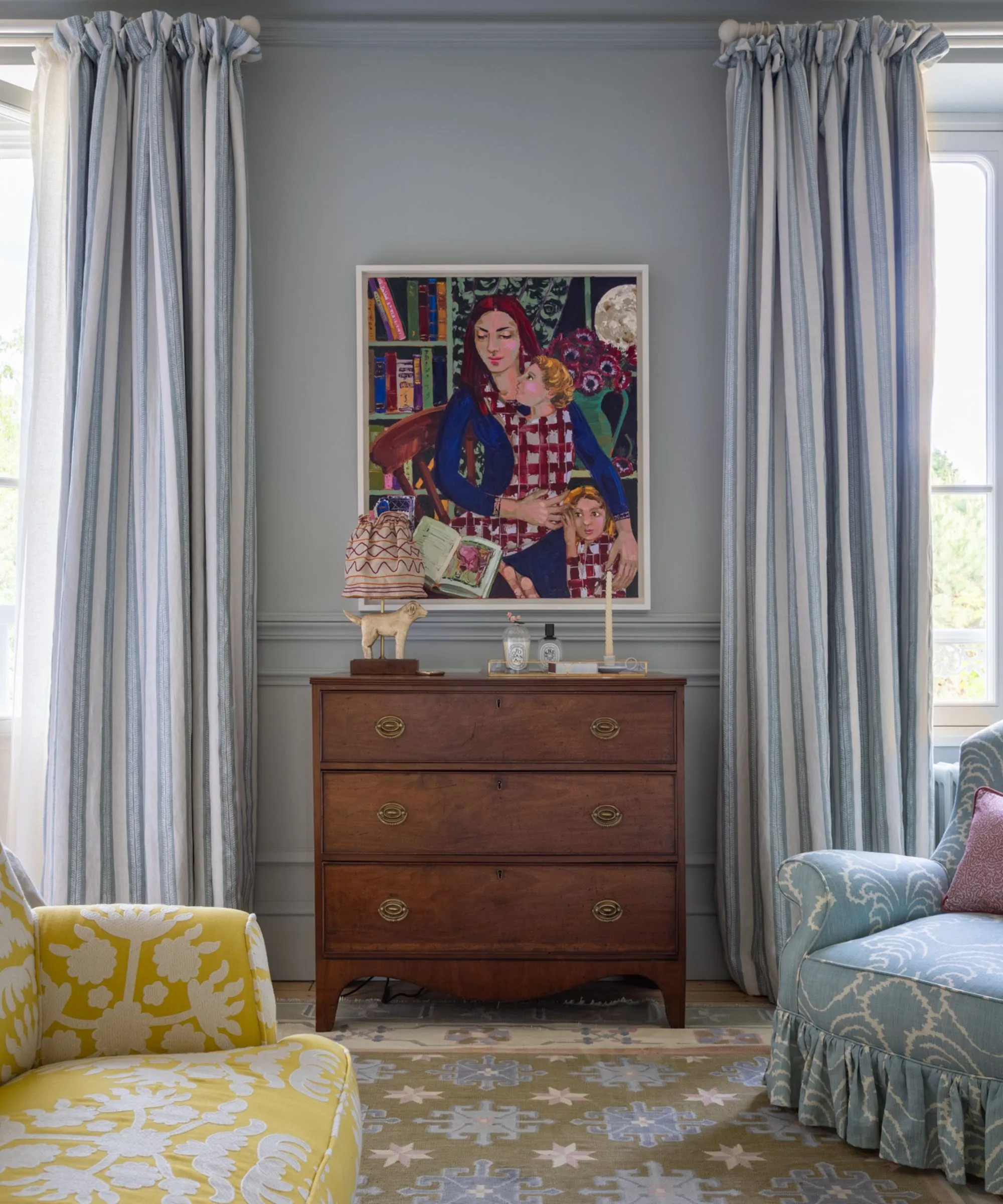 dormitorio azul con cortinas a rayas azules y blancas, un pie de cama amarillo, un sofá, una cómoda antigua y una pintura colorida' loading='lazy' title=