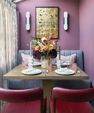 Sala de jantar roxa com cadeiras de couro vermelho e pequena mesa quadrada