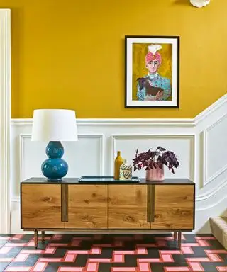 Eine moderne Fluridee mit gelben Wänden, weißen Holzarbeiten und einem modernen Mid-Century-Sideboard aus Holz