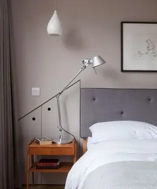 Ein graues Schlafzimmer mit einer weißen Deckenpendelleuchte und einer Tischlampe