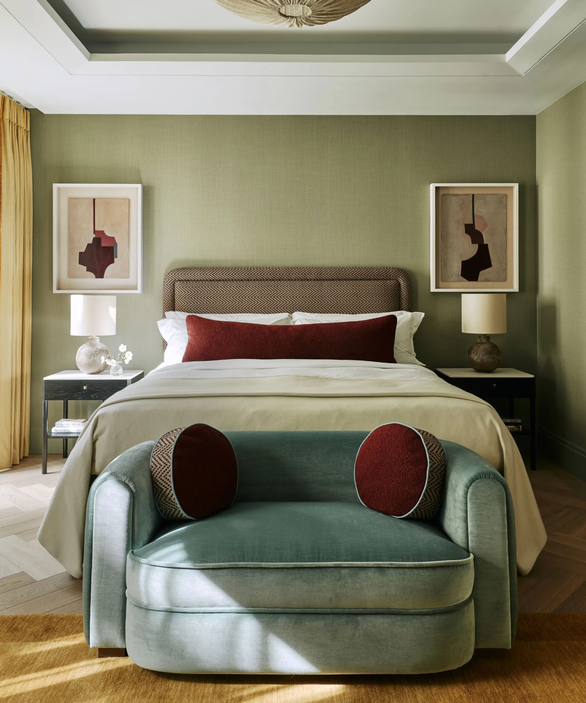 Acogedor dormitorio verde terroso moderno con paredes verdes una cama grande neutral diseñada con una almohada lumbar de terciopelo rojo Un sofá pequeño de terciopelo azul al pie de la cama con almohadas redondas' loading='lazy' title=