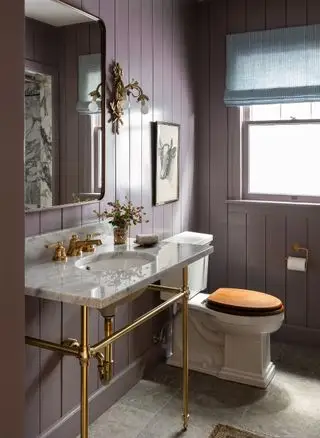 Pannelli viola a tutta lunghezza nel bagno con lavabo e WC in ceramica