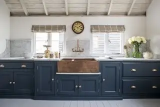 cucina blu con lavabo in rame, pareti bianche, tetto in legno, persiane, piano di lavoro in marmo e alzatina